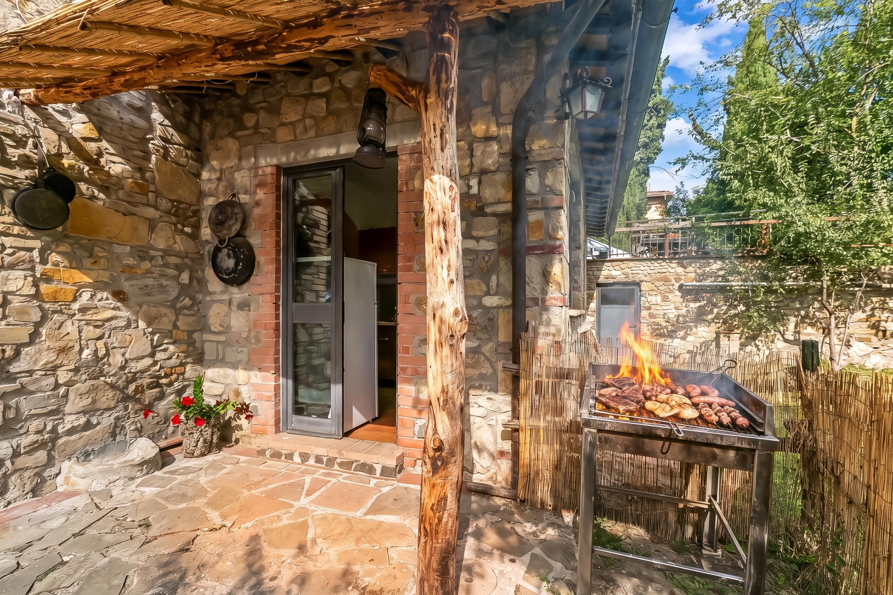 A stone building with a wooden door, a grill outside, and a stone wall.