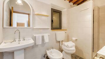 Ein Badezimmer mit Waschbecken, Spiegel, Toilette, Bidet und Handtuchhalter.