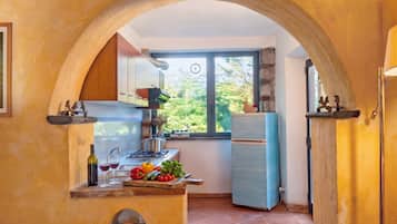 A kitchen with a window, a stove, a refrigerator, and a sink.