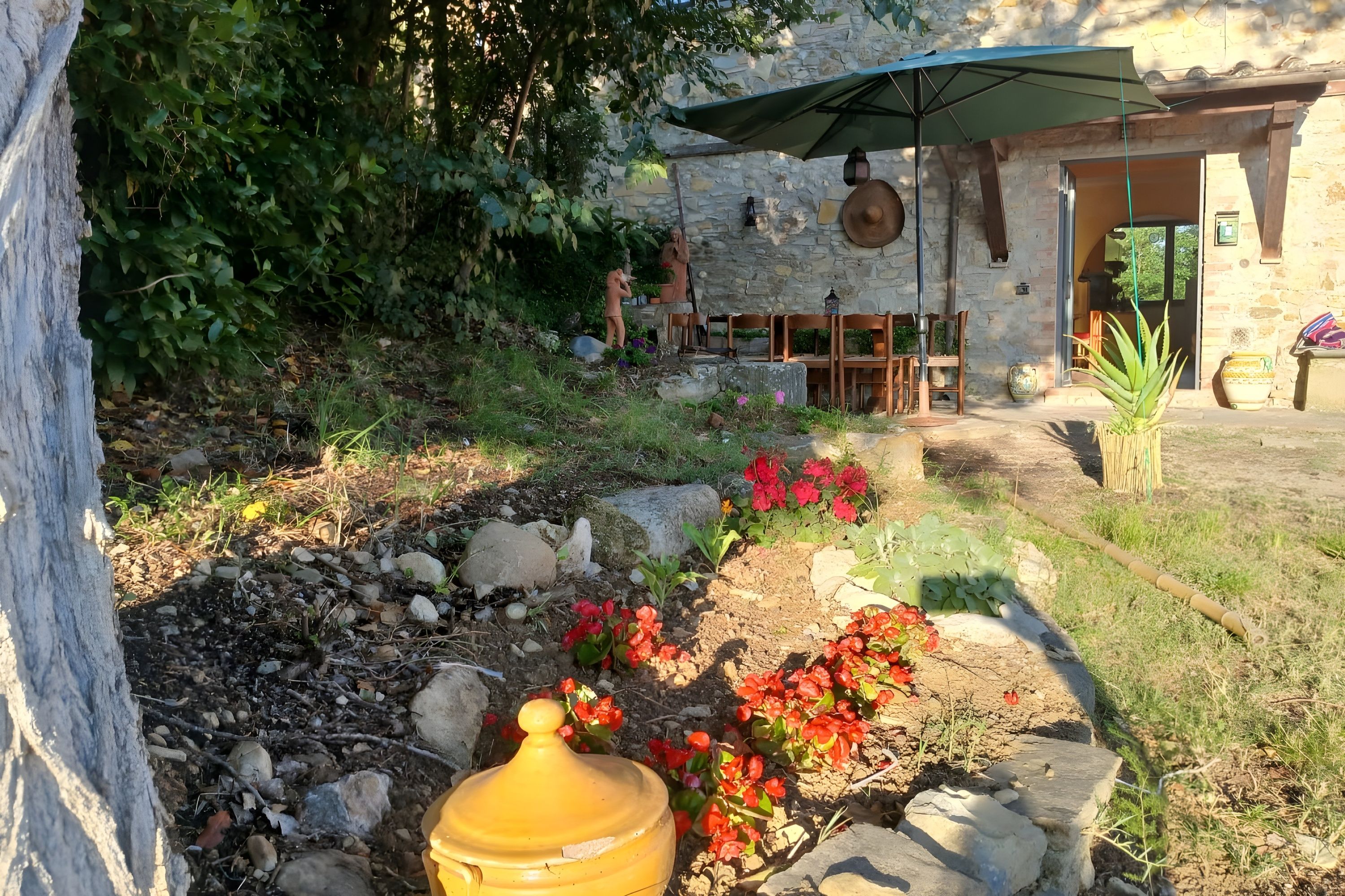 A rustic outdoor seating area with stone walls, a stone pathway, and potted plants.