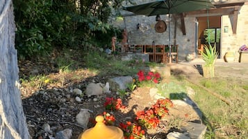 A rustic outdoor seating area with stone walls, a stone pathway, and potted plants.