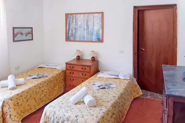 Quarto com duas camas, um aparador de madeira, um quadro e uma porta.