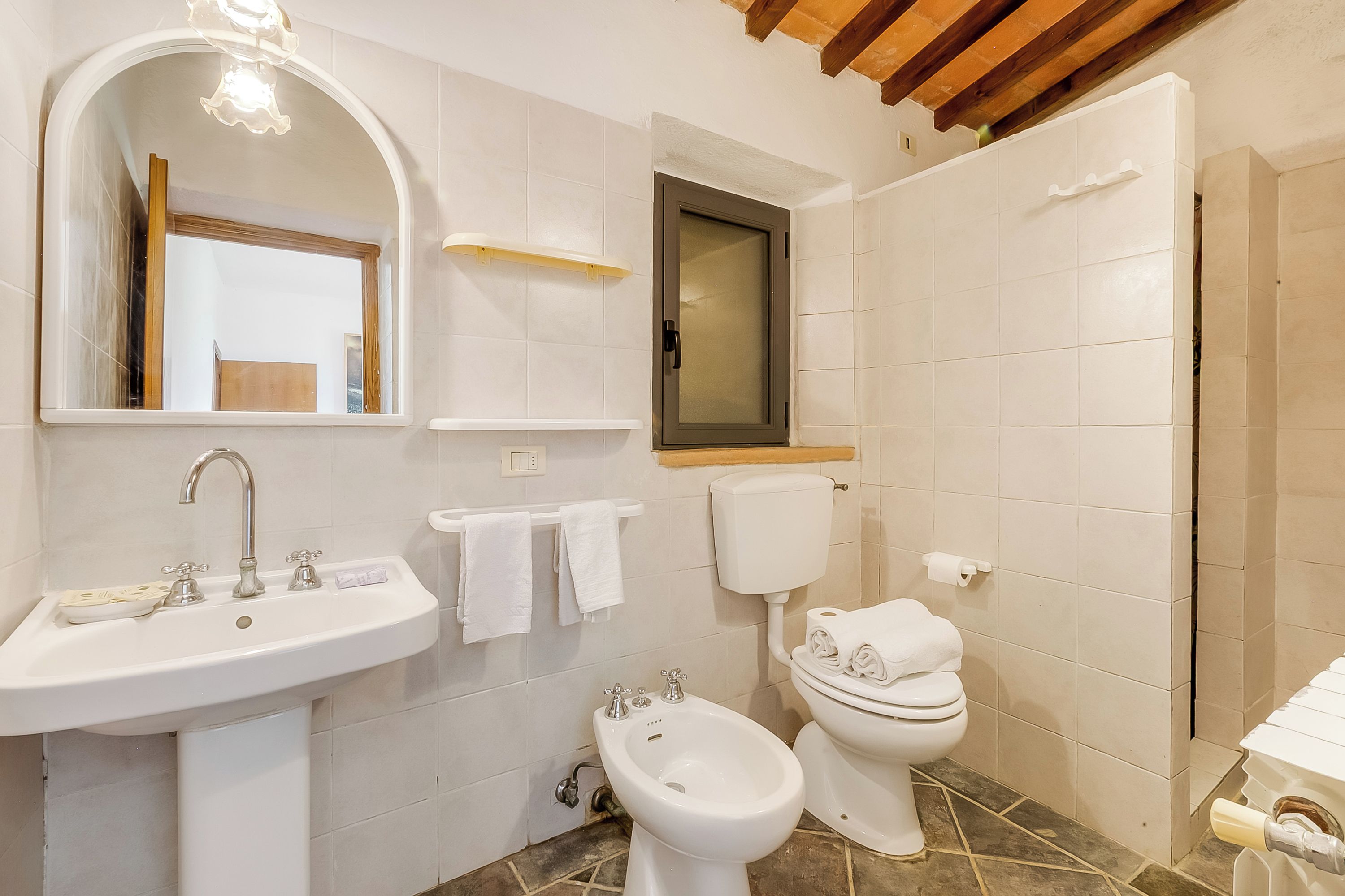 Un baño con lavamanos, espejo, inodoro, bidé y toallero.