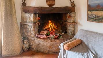 Una chimenea de piedra con fuego, un fuste de madera rústico y una cortina con diseño.