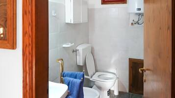 Un baño con inodoro, lavamanos y perchero para toallas.