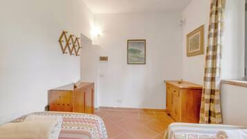 Un dormitorio con dos camas, un aparador de madera, un cuadro en la pared y una ventana con cortinas.