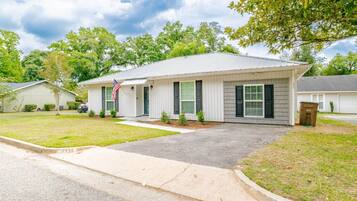 A single-story residential building with a front porch, a flag, and a well-maintained lawn.