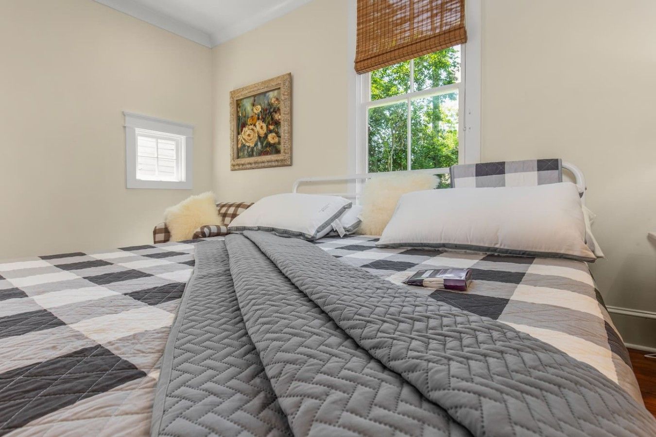 Un dormitorio con una cama grande, una ventana con vistas a árboles y un cuadro en la pared.