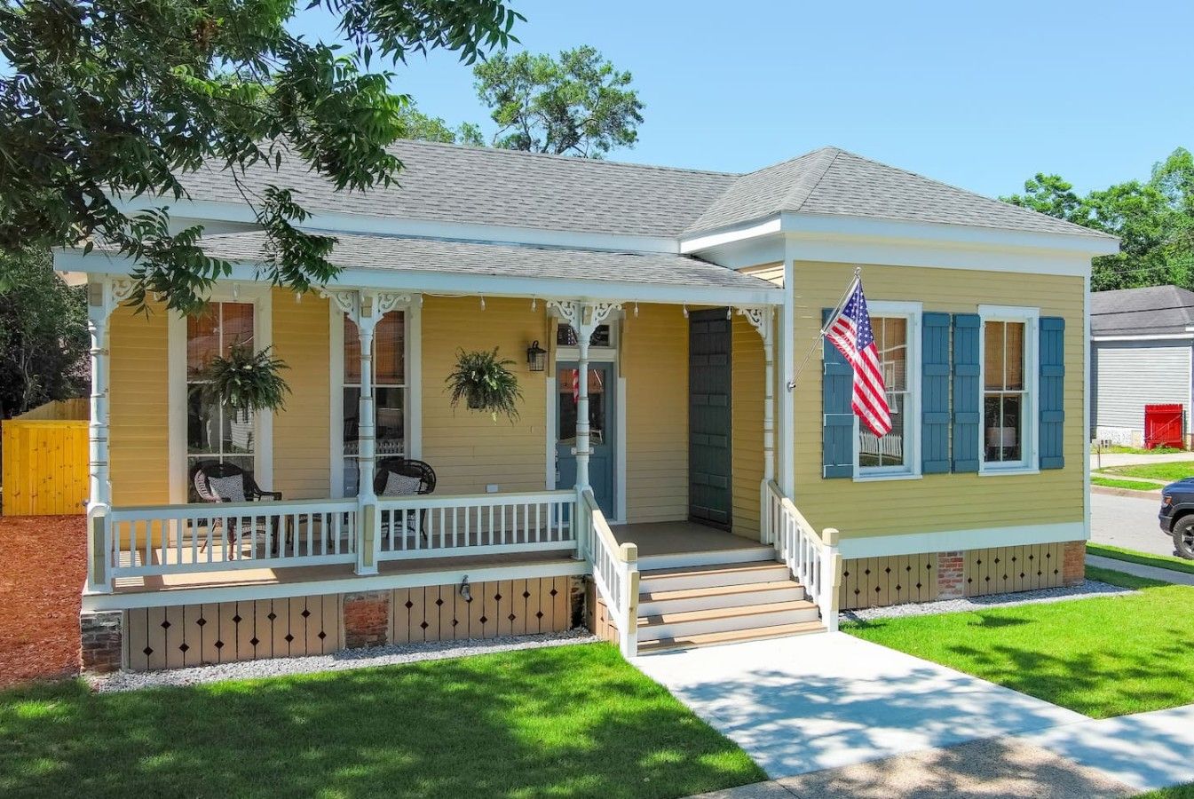 A single-story house with a porch, a flag, and a small front yard.