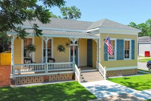A single-story house with a porch, a flag, and a small front yard. - White House On University (Mobile)