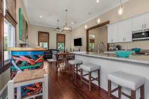 Cocina moderna con barra, suelo de madera y comedor con vistas.