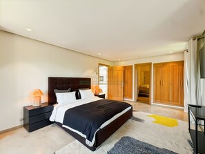 A bedroom with a bed, bedside tables, a lamp, a wardrobe, and a television. - Propriété d’exception à Samanah Golf (marrakech)