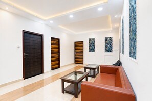 Un interior moderno con una puerta de madera, una mesa con superficie de vidrio, un sofá de cuero y obras de arte enmarcadas en las paredes.