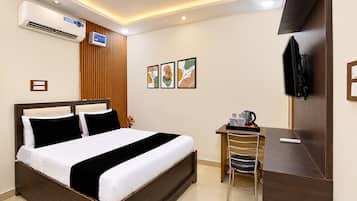 Ein Hotelzimmer mit Bett, Schreibtisch, Stuhl, Fernseher und Bildern an der Wand.