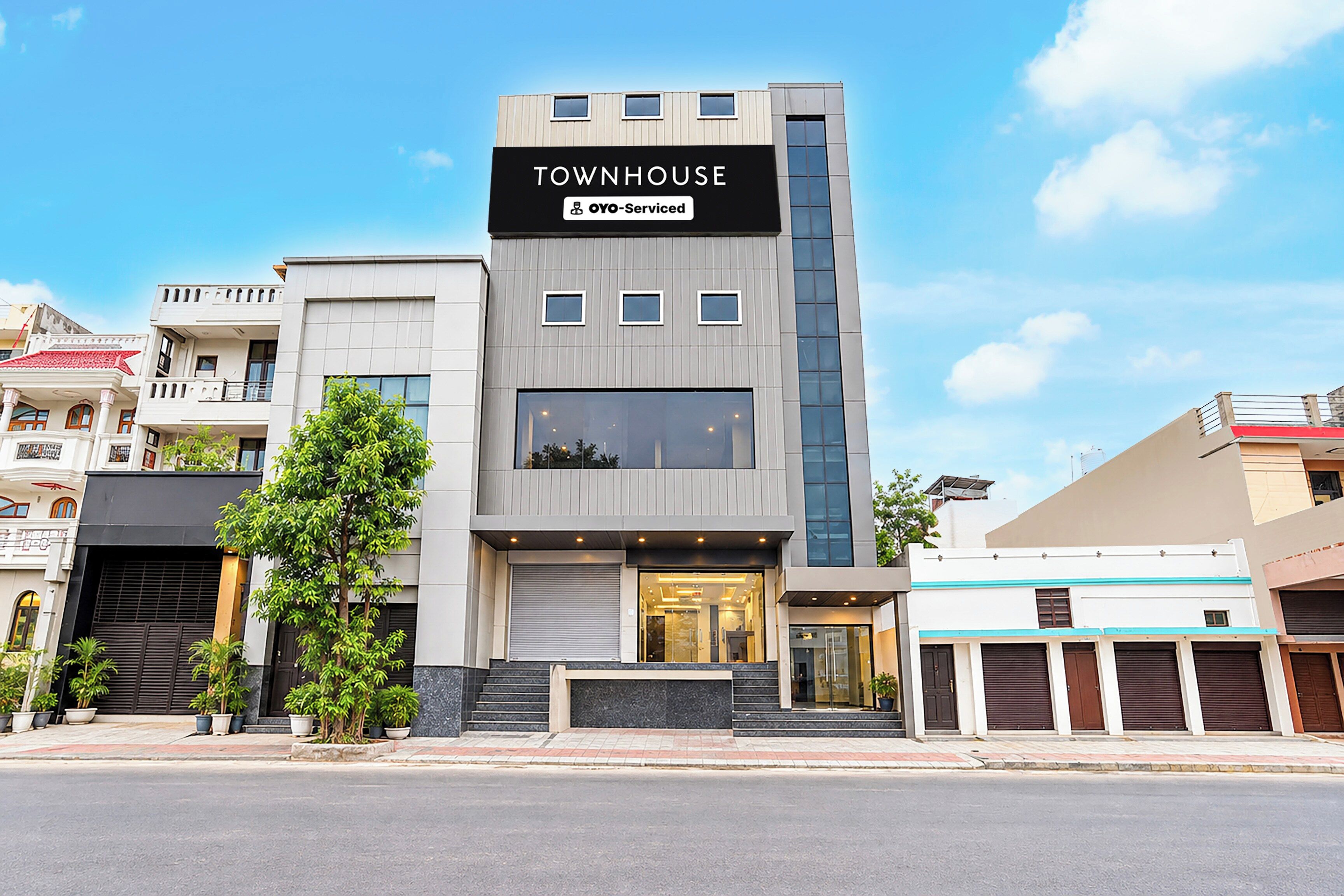 A modern townhouse with a prominent 'TOWNHOUSE' sign, a visible entrance, and a large window on the ground floor.