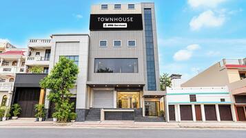 A modern townhouse with a prominent 'TOWNHOUSE' sign, a visible entrance, and a large window on the ground floor.