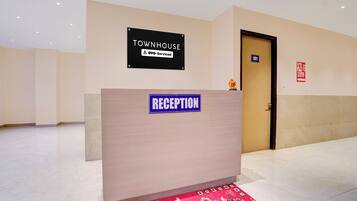 A reception desk with a sign indicating it's a townhouse serviced by OYO. There's a fire exit sign on the wall and a door marked with the number 101.