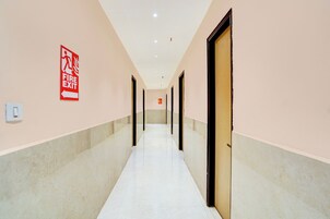 A corridor with a fire exit sign, doors, and a light switch on the wall.