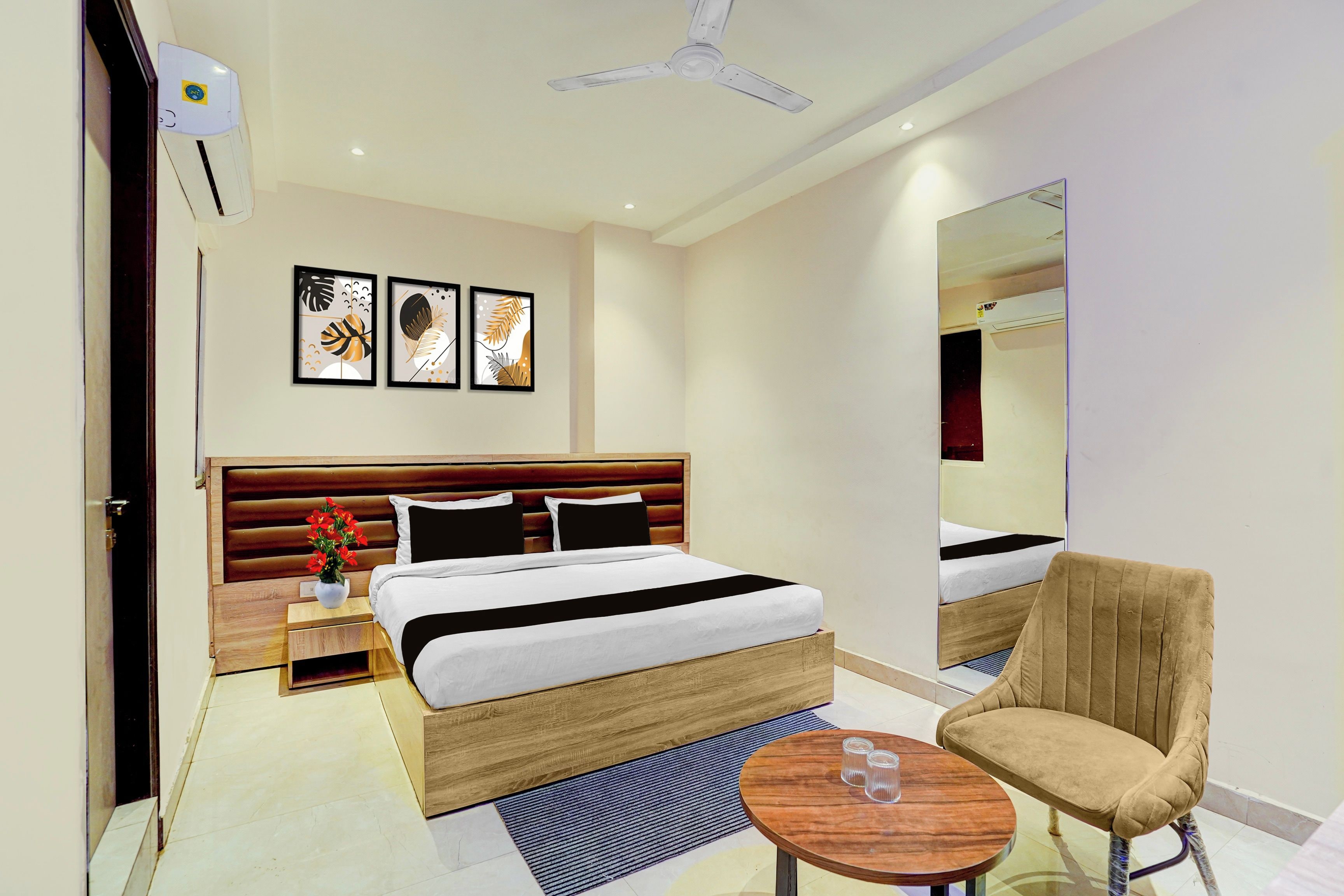Habitación de hotel con cama, mesita de noche, silla, mesa redonda y una obra de arte en la pared.