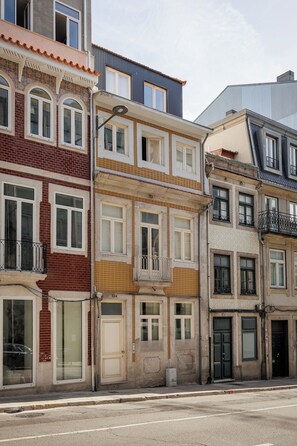 A row of multi-story buildings with distinct architectural styles, including a mix of brick and stucco facades, large windows, and balconies. - Authentic Porto Retreat with Private Patio (Porto)