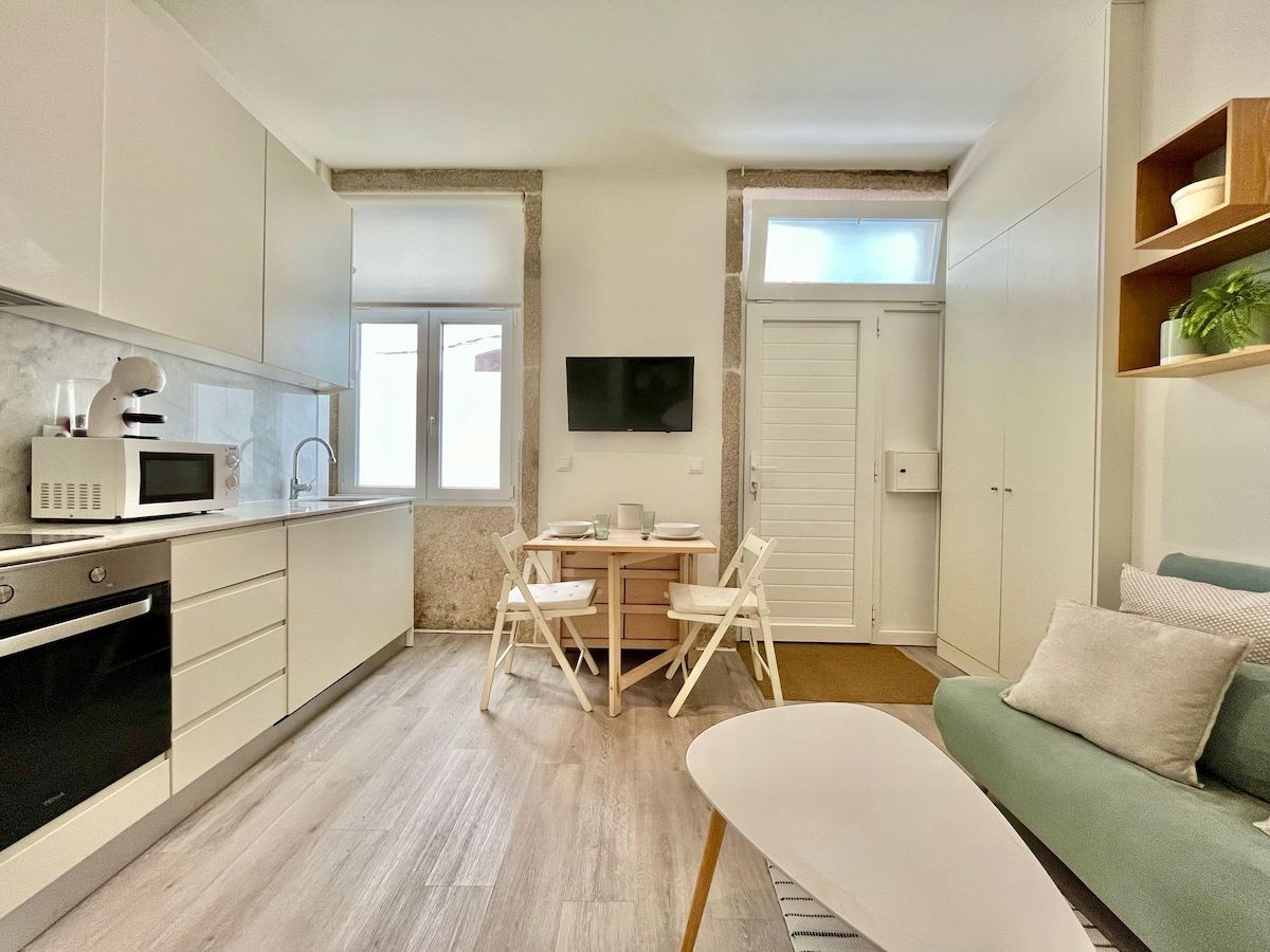 Une cuisine compacte comprenant une table et des chaises, un four à micro-ondes et un téléviseur fixé au mur.