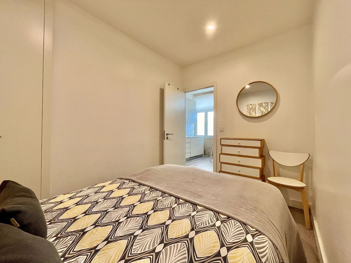 Une chambre à coucher avec un lit, une commode, une chaise et un miroir au mur.