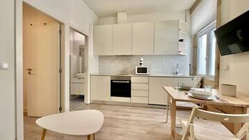 A modern kitchen with white cabinets, a microwave, and a dining area with a table and chairs.