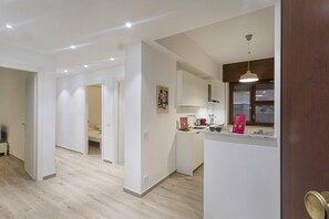 A modern kitchen with white cabinets, a wooden countertop, and a hanging pendant light. - XXV Aprile By Wonderful Italy - Menta (Genoa)