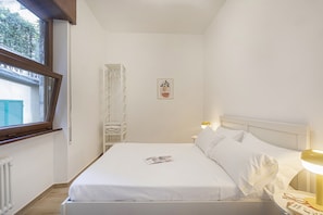 A bedroom with a bed, bedside lamps, a window, and a radiator. - XXV Aprile By Wonderful Italy - Menta (Genoa)
