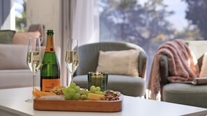 Et bord med en champagneflaske, to glas og et fad med frugt.