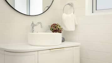 A bathroom with a white sink, a round mirror, and a towel rack.