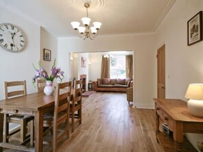 A dining area with a wooden table and chairs, a vase with flowers, and a clock on the wall. - Three bedroom  in United Kingdom of Great Britain and Northern Ireland, Norwich (Norwich)