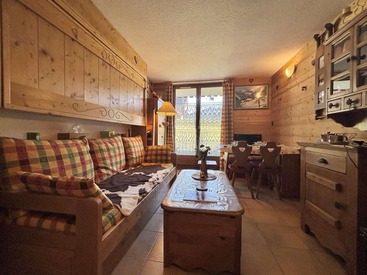 A cozy room with a sofa, a dining table, and wooden cabinets.