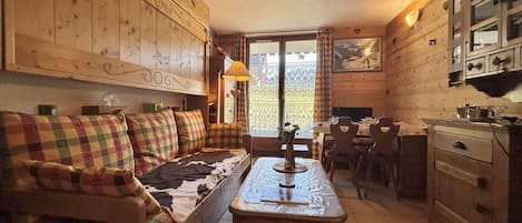 Una habitación acogedora con sofá, una mesa de comedor y armarios de madera.