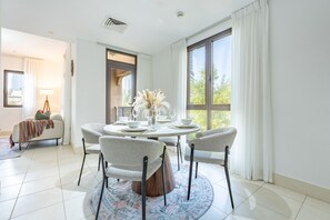 A dining area with a round table, chairs, and a vase of flowers. - Burj Khalifa View 2BR in the Heart of Downtown, Short Walk from Wings of Mexico (Dubai)