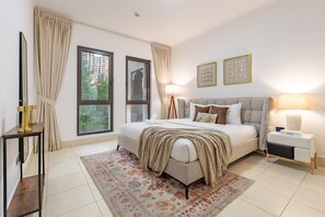 A modern bedroom with a large bed, bedside lamps, a nightstand, a decorative rug, and two framed artworks on the wall. - Burj Khalifa View 2BR in the Heart of Downtown, Short Walk from Wings of Mexico (Dubai)