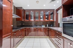 A kitchen with wooden cabinets, a stainless steel sink, and a built-in oven. - Burj Khalifa View 2BR in the Heart of Downtown, Short Walk from Wings of Mexico (Dubai)