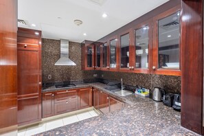 A modern kitchen with wooden cabinets, a stainless steel range hood, and a granite countertop. - Burj Khalifa View 2BR in the Heart of Downtown, Short Walk from Wings of Mexico (Dubai)