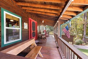 Een houten veranda met een bankje, een rode deur en een Amerikaanse vlag.