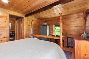 A wooden cabin room with a four-poster bed, a wooden dresser, and a window with a view of a green landscape. - Cozy 3BR Mountain Cabin | Peaceful & Relaxing (Murphy)