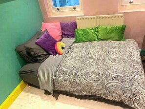 A bed with a patterned bedspread, multiple pillows, and a striped blanket. - Big, grand apartment in Bayswater on edge of Hyde Park/Kensington Gardens (London)