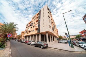 Ein mehrgeschossiges Gebäude mit moderner Architektur, das einen markanten Eingang und eine Reihe von Balkonen zeigt.