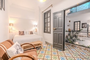 A hotel room with a bed, two chairs, a small table, a door, and a balcony with a railing. - Riad Des Sables • Pool • 15 min walk Jemaa El Fna (Marrakesh)