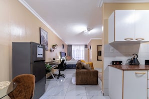 Un espacio habitable compacto con kitchenette, comedor y un dormitorio.