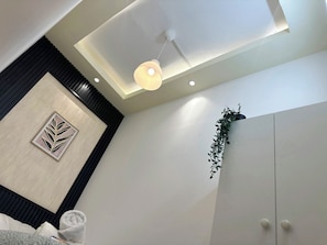 A modern room with a ceiling light, a framed artwork, a potted plant, and a white wardrobe. - Quiet Partition Room in Tecom Near Metro (Dubai)