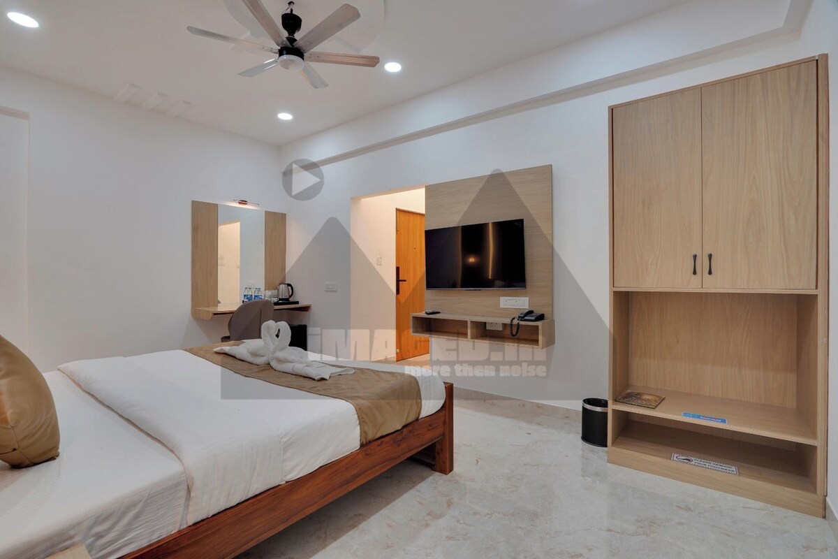 A modern hotel room with a bed, a television, a wardrobe, and a ceiling fan.