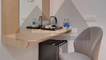 Een moderne hotelkamer met een ingebouwd bureau, een stoel, een koffiezetapparaat en een minibar.