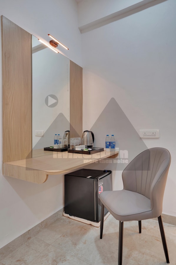 Una habitación de hotel moderna con escritorio integrado, una silla, máquina de café y mini refrigerador.