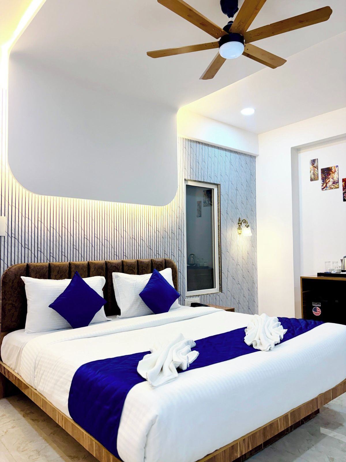 Una habitación de hotel con cama, ventilador de techo, ventana y puerta.