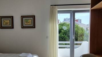 A modern bedroom with a bed, a chair, and a view through a large window.